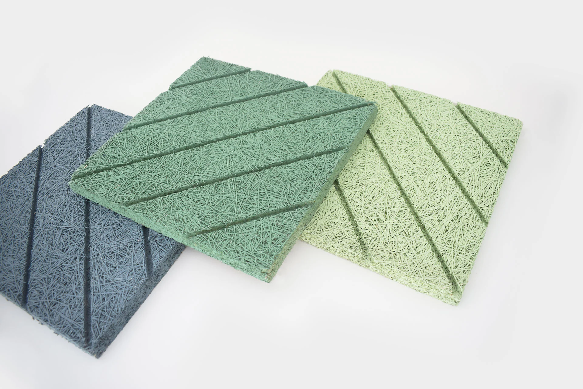 Three square acoustic panels in blue, green, and light green colors, each with a textured, fibrous surface and diagonal grooves, displayed on a white background.