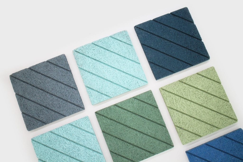 Eight square tiles in shades of blue and green are arranged neatly on a white background. Each tile has diagonal grooved lines, creating a textured pattern.