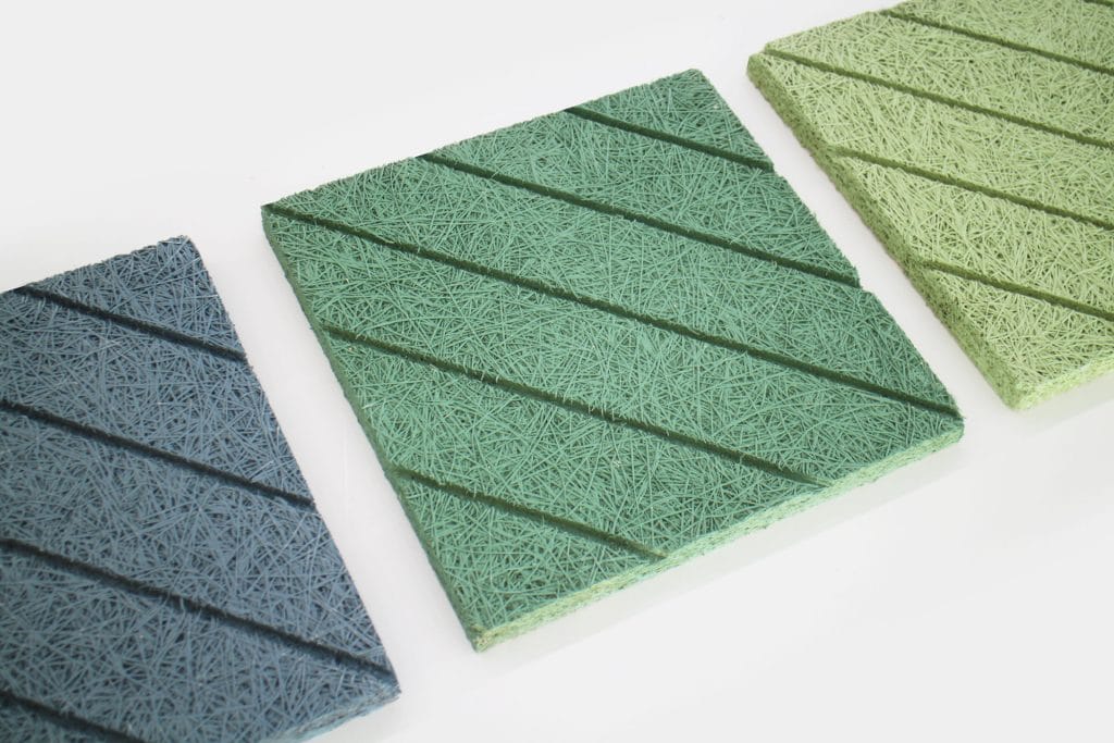 Three square acoustic panels in blue, green, and light green, each with a textured, fibrous surface and diagonal grooves, are arranged side by side on a white background.