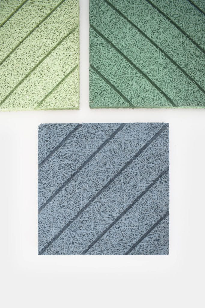 Three rectangular sound-absorbing panels, each with a textured, string-like surface and diagonal grooves, are displayed on a white background. The panels are light green, dark green, and blue.
