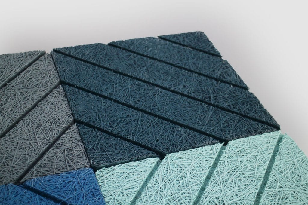 A close-up view of textured, geometric panels in shades of blue and gray, arranged in a pattern with diagonal grooves and a fibrous surface.