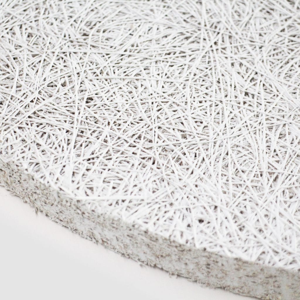Close-up of a textured, white material composed of tangled, thin fibers or strands, forming a rough, interwoven surface with a thick edge.