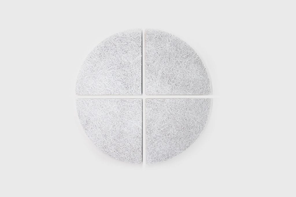 Four textured, quarter-circle white panels are arranged to form a circle with a cross-shaped gap between them, placed on a plain light gray background.