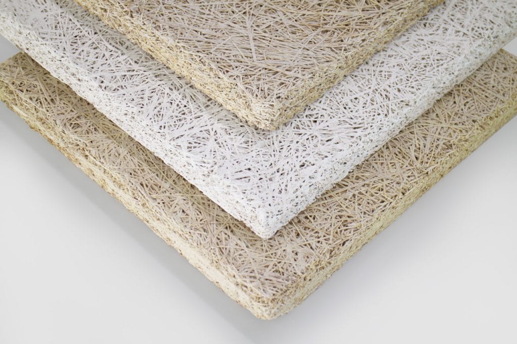 Three rectangular fiberboard panels stacked diagonally, each with a rough, straw-like texture. The panels are in shades of white and beige, displayed against a plain light background.