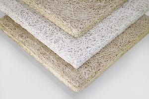 Three rectangular fiberboard panels stacked diagonally, each with a rough, straw-like texture. The panels are in shades of white and beige, displayed against a plain light background.