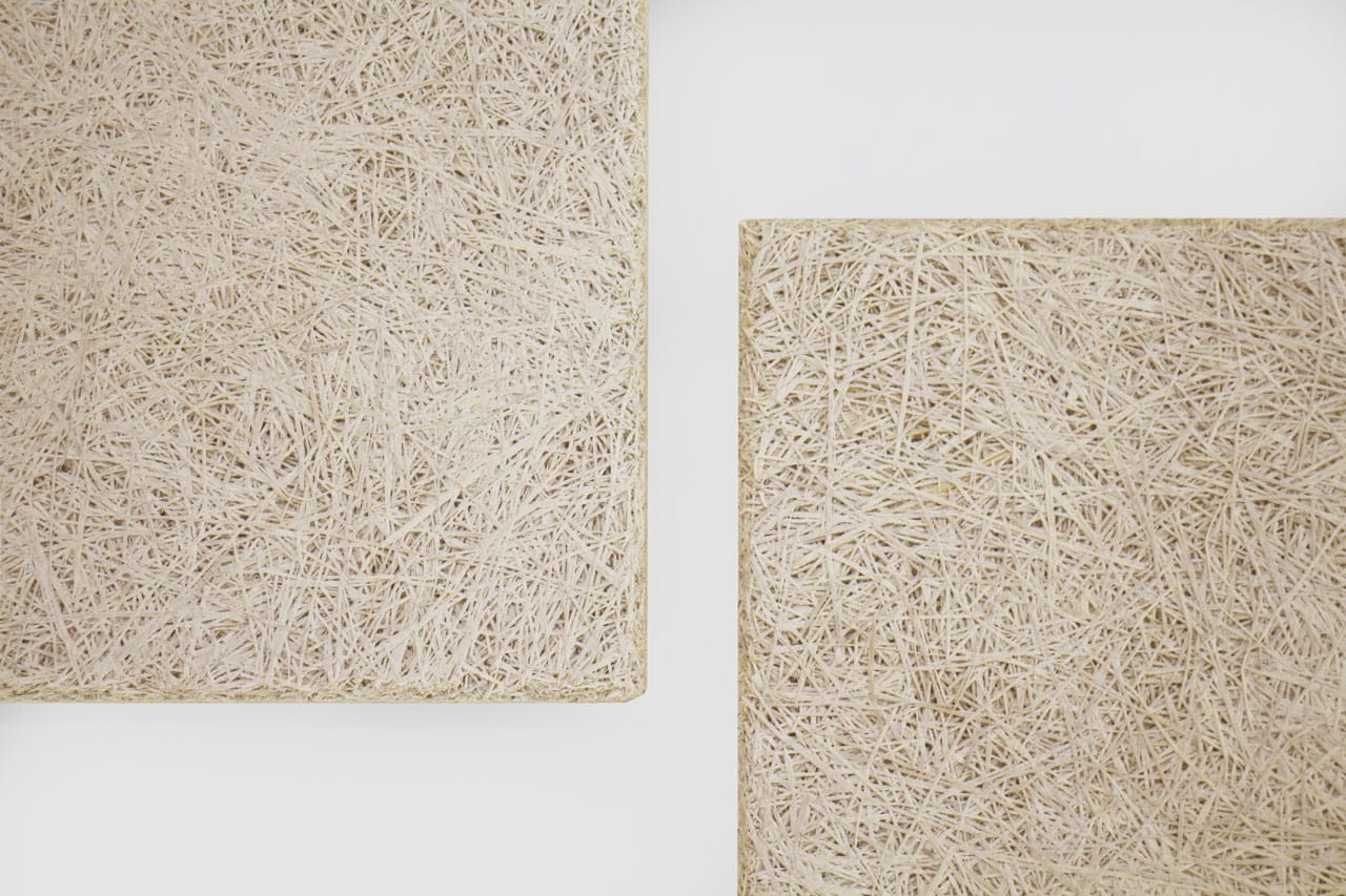 Two beige rectangular panels with textured, tangled straw-like surfaces are placed on a white background, with their corners visible and separated by negative space.