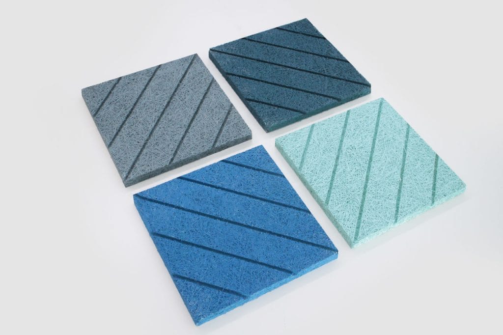 Four square textured tiles are arranged in a grid on a white background. Each tile is a different shade of blue or gray and features diagonal grooves across its surface.