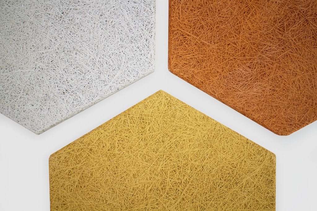 Three textured, hexagonal panels in white, orange, and yellow are arranged closely together on a white background. Each panel has a fibrous, woven surface pattern.