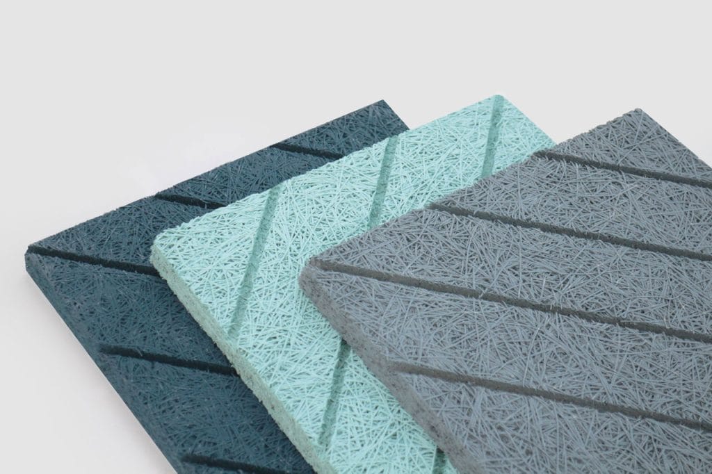 Three textured panels in dark teal, light teal, and gray colors, each with diagonal grooves and a fibrous, string-like surface, are arranged in a staggered stack against a light background.