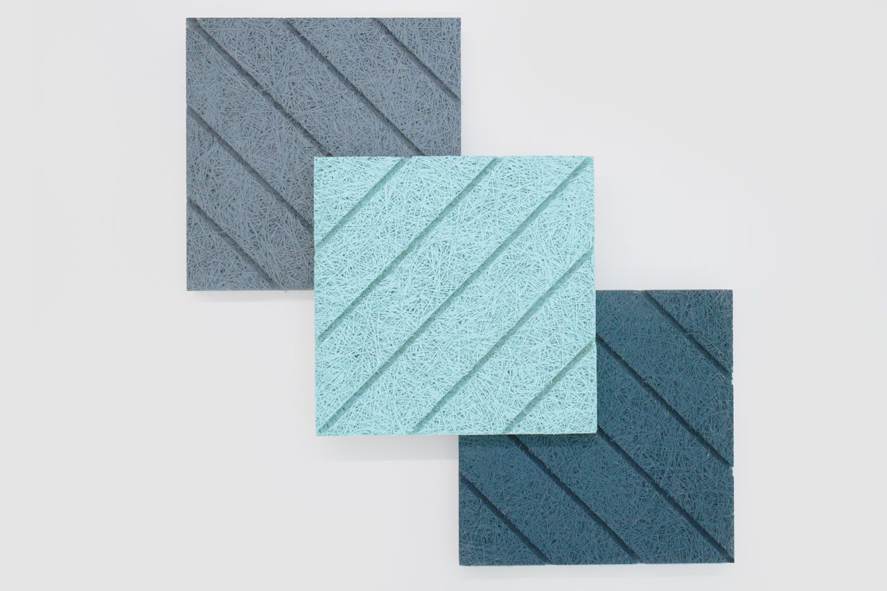 Three textured square panels with diagonal grooves are arranged in a row. The top left panel is gray, the center panel is light blue, and the bottom right panel is dark blue, all set against a white background.